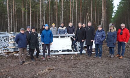 Eine Gruppe steht neben einem Stahlelement für einen Windmessmast