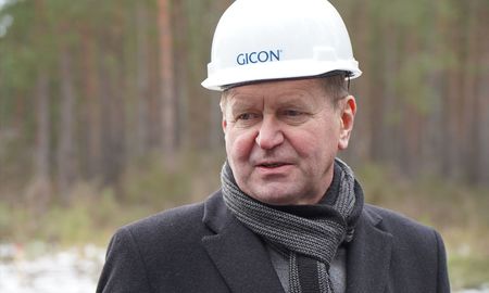 The District Administrator of Oberspreewald-Lausitz, Siegurd Heinze, stands on the construction site wearing a construction helmet. He is wearing a scarf and a winter jacket.