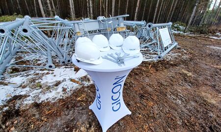 Ein Tisch mit fünf Bauhelmen und fünf Maulschlüsseln stehen neben Bauelementen für einen WIndmessmast.